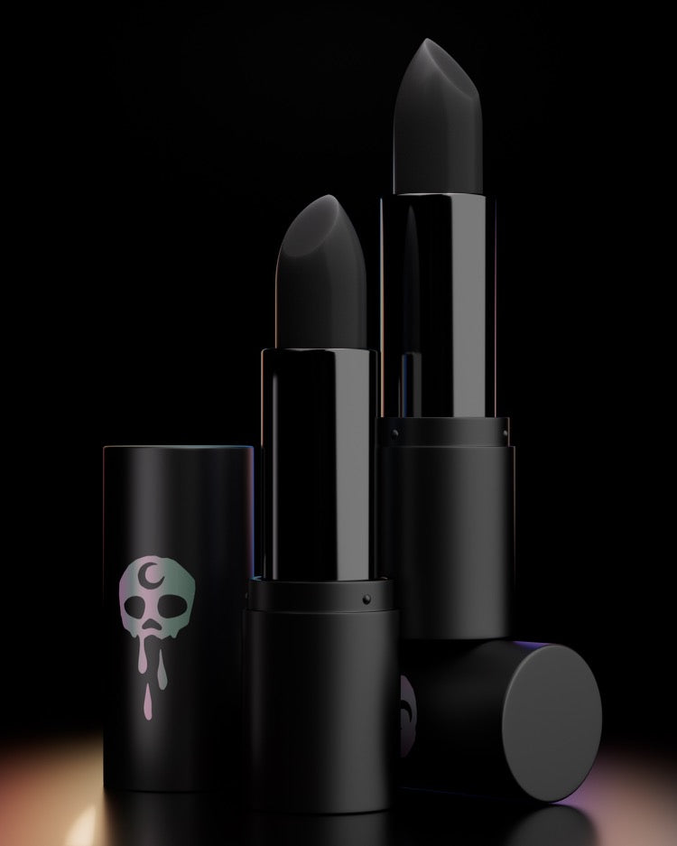 Three black colored lipsticks with The Funeral Portrait band logo on the packaging displayed against a dark background.